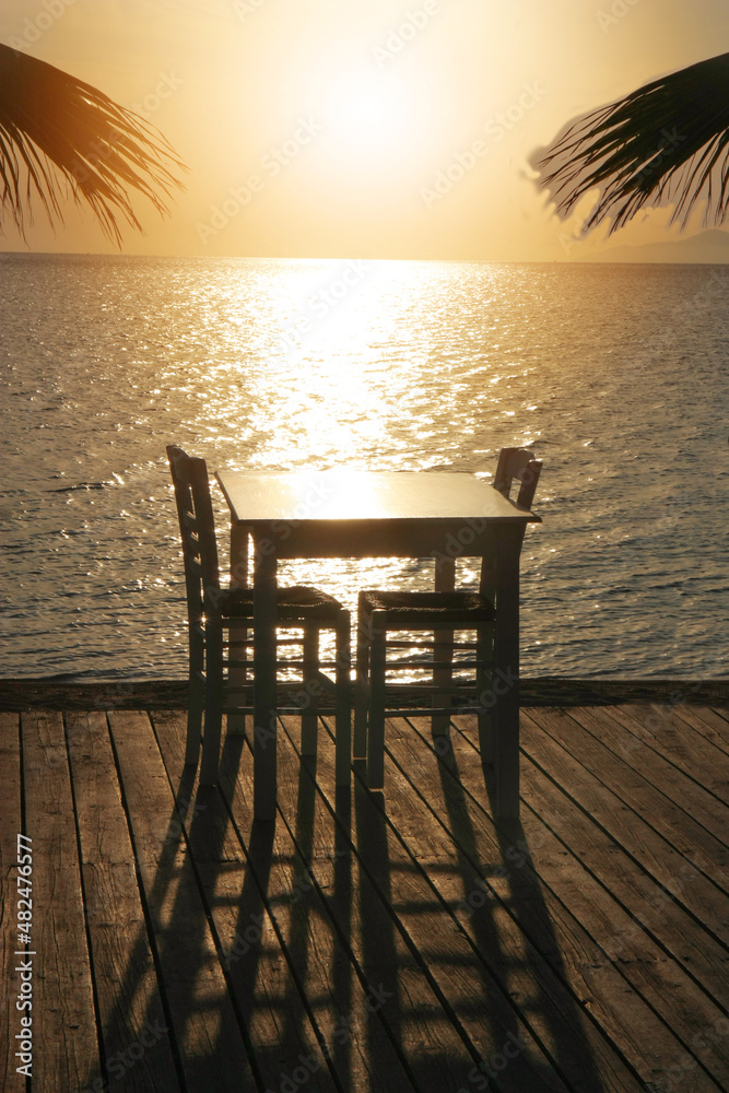 Romantic scene on the beach with a table for two at the restaurant during sunset