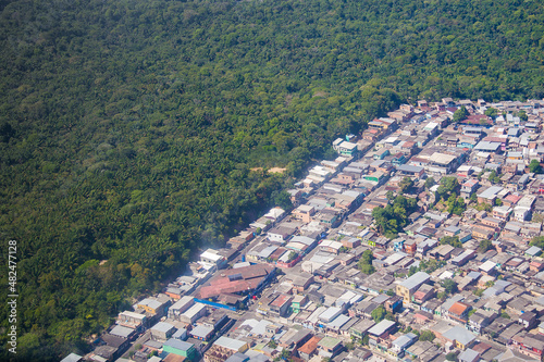 A Deforested area in tthe city of Manaus, in the Brazilian Amazon. A green forest in the background with a  a village in the edge. photo