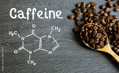 coffee beans with spoon and chemical structure of caffeine on a wooden table