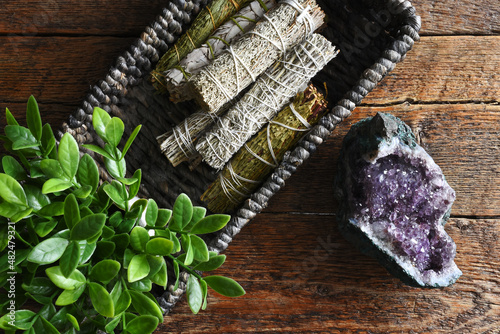 A top view image of several healing smudge sticks with amethyst geode on a dark wooden table. 