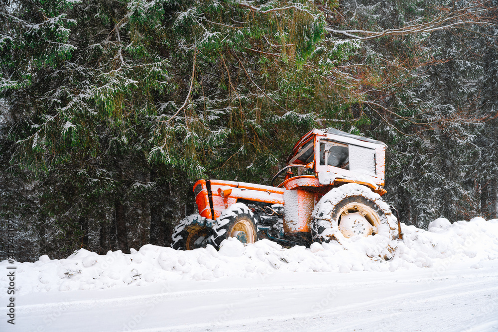 Tractor stuck in snow by the road in winter forest Tractor stuck in snow by the road in winter forest