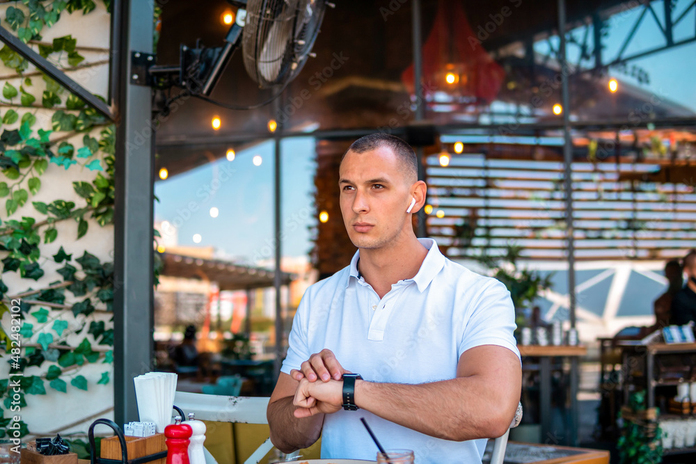 Businessman eating in a restaurant and checking messages on his smartwatch