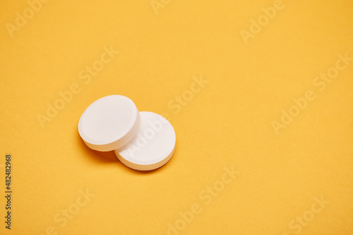 Pharmaceuticals medicament two tablet round white pills medicine top view isolated on the bright solid yellow fond background