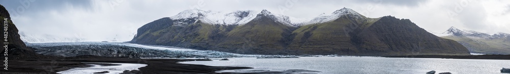 Skaftafellsjökull glacier, Iceland. Glacier tongue slides from the Vatnajökull icecap or Vatna Glacier near subglacial Esjufjöll volcano. Glacial lagoon with ice blocks and surrounding mountains.