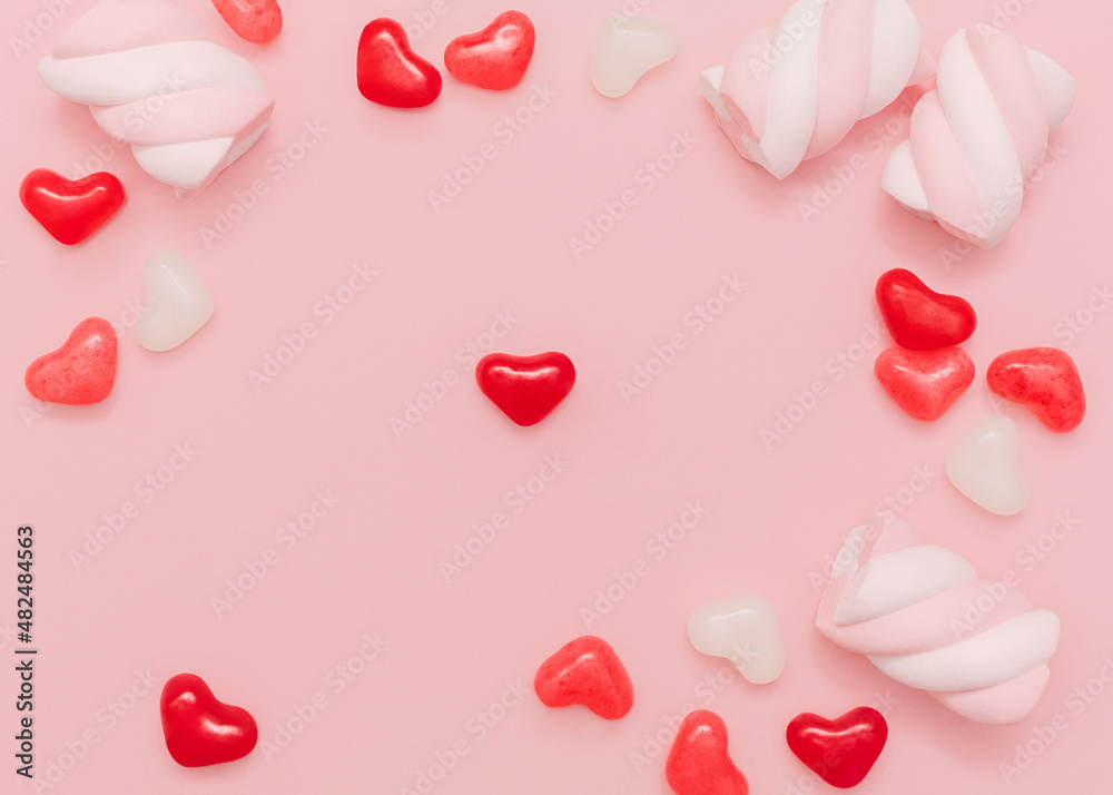 Sweet food. Top view photo with copy space. Colorful jelly candies in heart shape and marshmallows on pink desk