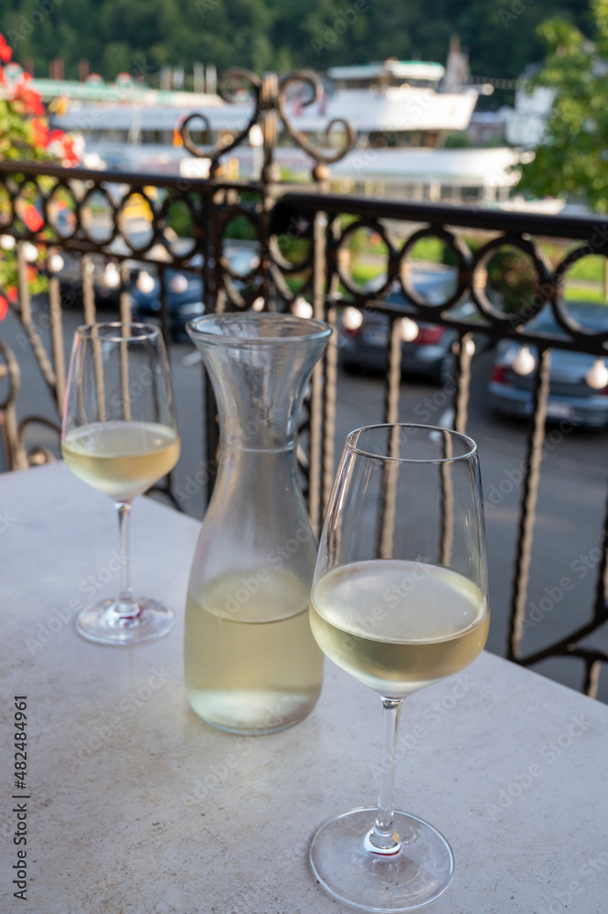 Obraz premium Tasting of white quality riesling wine served on outdoor terrace in Mosel wine region and old German town on background, Germany
