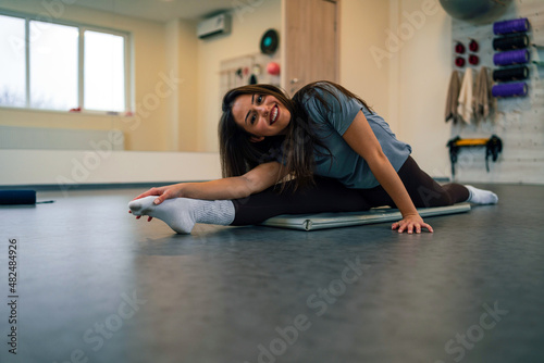 Young attractive woman doing splits while training in the gym