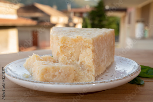 Cheese collection, piece of matured cow cheese pasmesan parmigiano reggiano and Italian houses on background