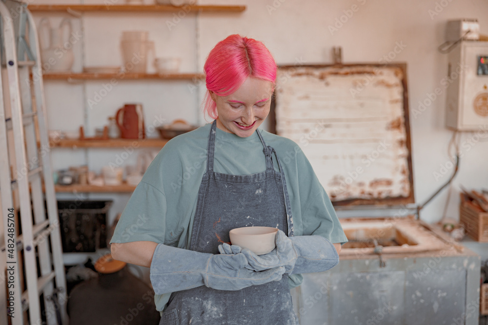 Young female potter engaged in craft in her workshop Young female potter engaged in craft in her workshop