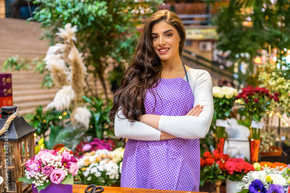 Portrait of a beautiful and smiling florist behind the counter in the flower shop