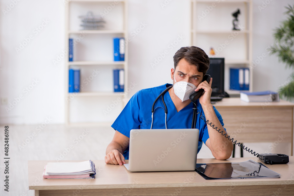 Young male doctor working in the clinic during pandemic Young male doctor working in the clinic during pandemic