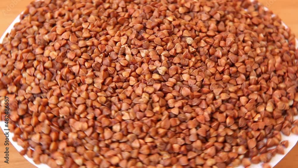 Buckwheat porridge grains move around on brown background, healthy food Buckwheat porridge grains move around on brown background, healthy food