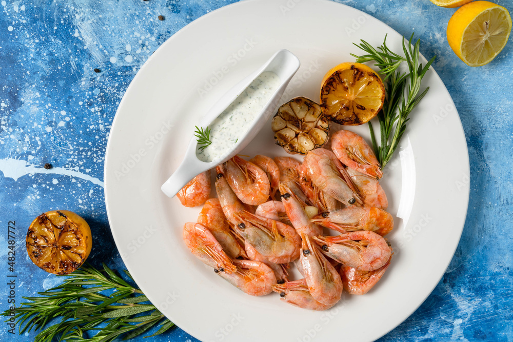 Pink shrimps with lemon on a blue abstract background. Healthy nutrition concept. Mediterranean diet, delicacies. Flat lay. Pink shrimps with lemon on a blue abstract background. Healthy nutrition concept. Mediterranean diet, delicacies. Flat lay.