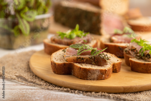 Bread sandwiches with jerky salted meat, sorrel and cilantro microgreen on white. side view, selective focus.