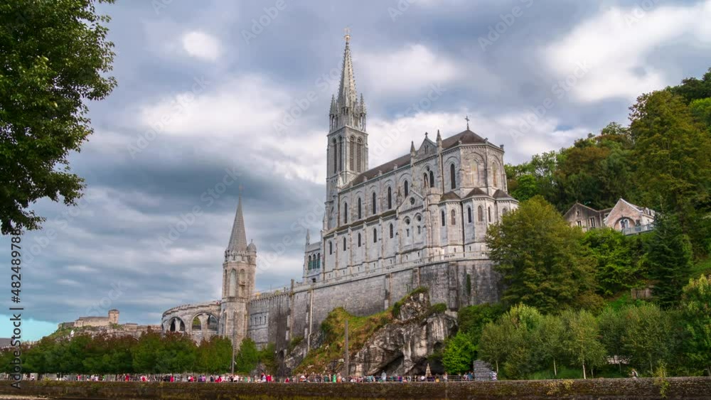 Lourdes, France - August 28, 2021: Time lapse of moving clouds and pilgrimage basilica of Holy Mary in Lourdes Lourdes, France - August 28, 2021: Time lapse of moving clouds and pilgrimage basilica of Holy Mary in Lourdes