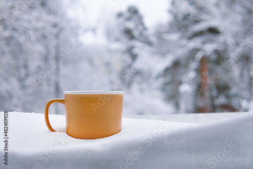 Brown mug with tea in the snow in winter