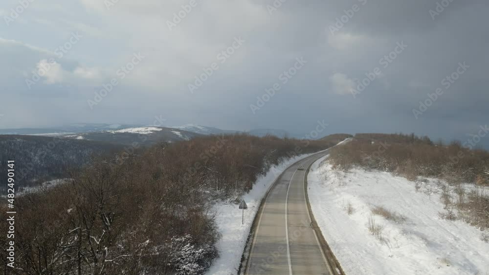 Travel journey transport and vacation concept High angle aerial view drone video on the road car driving in mountain range with white snow in winter day near Knjazevac in Serbia