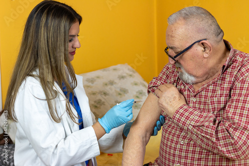 Immunizing homebound patients with covid-19 vaccine. Young doctor giving injection against covoravirus to elderly man
