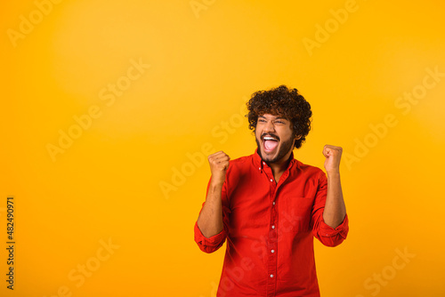 Extremely excited overjoyed man with beard shouting making yes gesture, amazed with his victory, triumph. Indoor studio shot isolated on yellow background