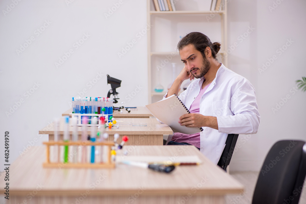 Young male chemist sitting at the desk in the classroom Young male chemist sitting at the desk in the classroom