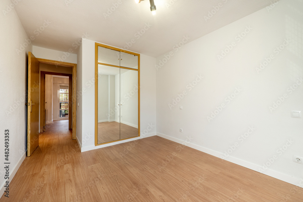 Fototapeta premium Room with built-in wardrobe with doors covered with mirrors and white painted walls