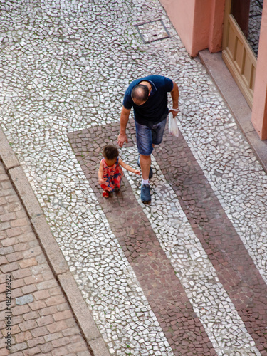 father and daughter walking on street seen from above