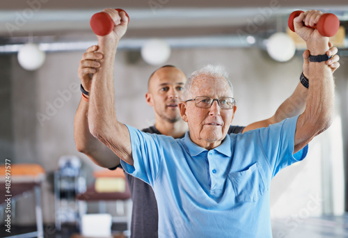 You can do it. Shot of a physiotherapist helping a senior man with weights. photo