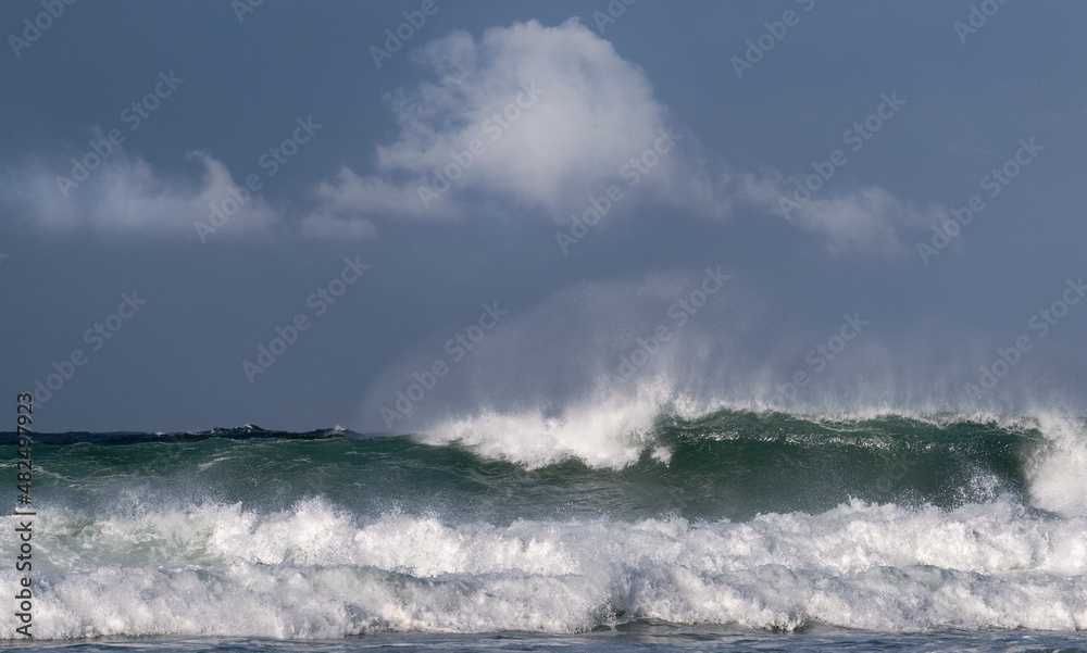 Seascape. Powerful ocean wave on the surface of the ocean. Wave breaks on a shallow bank. Stormy weather, stormy clouds sky background. Seascape. Powerful ocean wave on the surface of the ocean. Wave breaks on a shallow bank. Stormy weather, stormy clouds sky background.