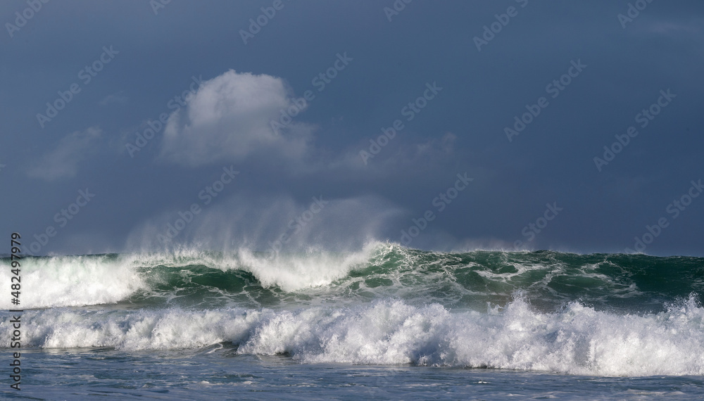 Seascape. Powerful ocean wave on the surface of the ocean. Wave breaks on a shallow bank. Stormy weather, stormy clouds sky background. Seascape. Powerful ocean wave on the surface of the ocean. Wave breaks on a shallow bank. Stormy weather, stormy clouds sky background.