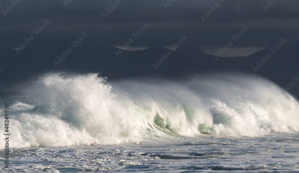 Obraz premium Seascape. Powerful ocean wave on the surface of the ocean. Wave breaks on a shallow bank. Stormy weather, stormy clouds sky background.