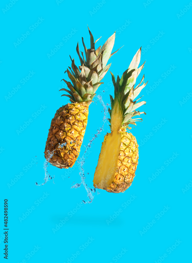 Sliced juicy pineapple with water splash on pastel blue background