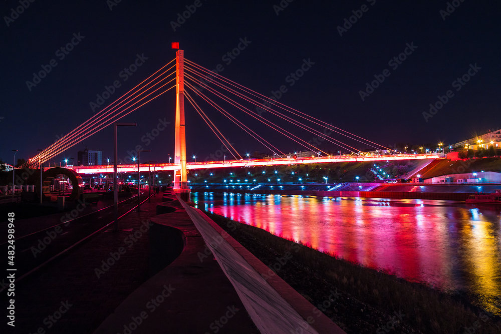 Beautiful view of the illuminated Bridge of Lovers over the Tura River at dusk, Tyumen, Russia
