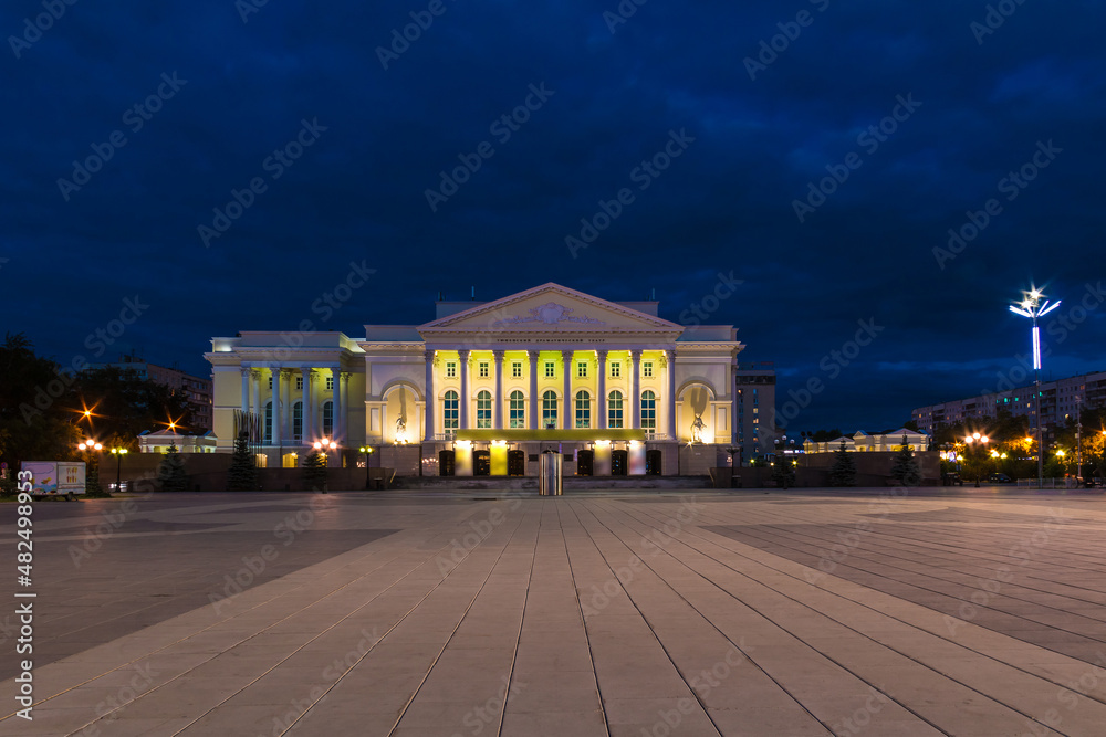 Beautiful view of the illuminated building of the Tyumen Big Drama Theater and the Square of the 400th Anniversary of Tyumen at twilight, Russia
