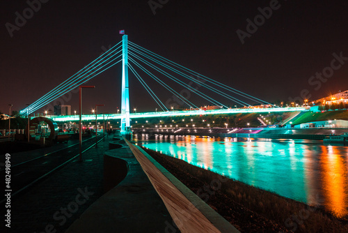 Beautiful view of the illuminated Bridge of Lovers over the Tura River at dusk, Tyumen, Russia 