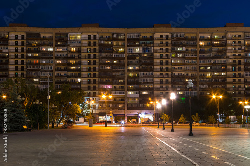 Beautiful view of illuminated facade of the apartment building called Muraveynik (Anthill) and the Square of the 400th Anniversary of Tyumen at twilight, Russia
 photo