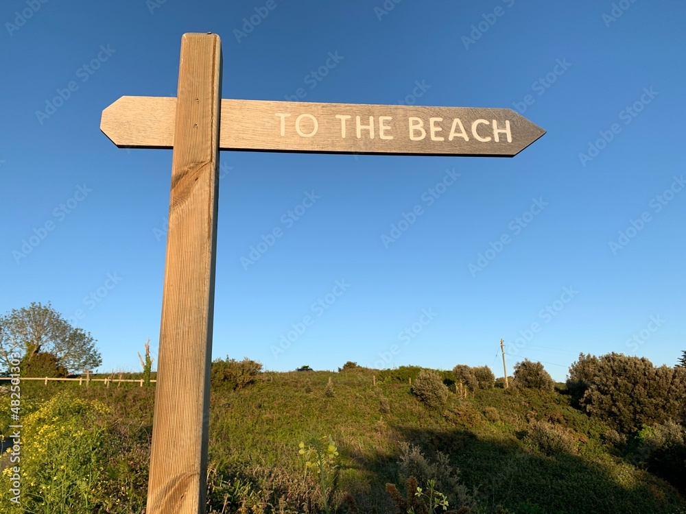 Natural wooden sign pointing the way to the beach in Portelet Bay, Jersey