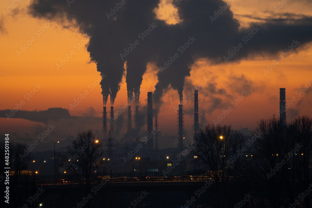 Winter industrial landscape. Coal-fired power station with smoking chimneys against dramatic sunset sky. Air pollution in city. Carbon dioxide CO2 emissions as primary driver of global climate change