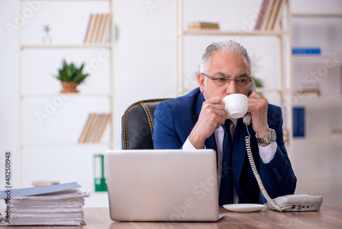 Old male employee drinking coffee during break