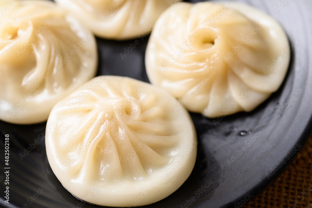 Xiao long bao, small Chinese steamed bun filling with minced pork on black plate