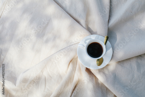 Hot Coffee in white cup on picnic blanket morning light background relaxing on holiday. Sunrays. Still life concept. Copy space. Colorful autumn picnic