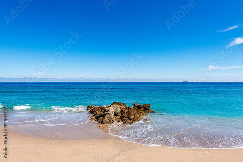 waves crashing on rocks and beach with ocean in Florida. Clear Blue sky with empty space 