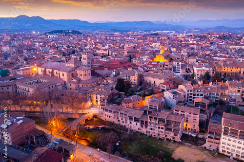 View from drone of Spanish town of Vic with tiled roofs of old buildings and ancient cathedral in winter evening, Barcelona province, Catalonia