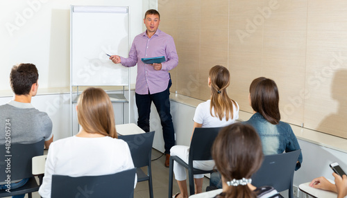 Positive experienced male business coach communicating with adult auditorium during training in office