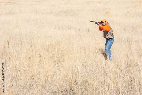 An adult male (upland game) pheasant hunter shooting a shotgun
