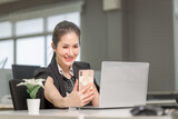 Cheerful businesswoman using phone in office. Excited pretty girl using smartphone in office, woman working in her home office
