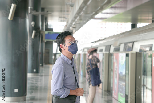 Wallpaper Mural Asian man commuter with face mask on standing on the subway platform waiting to go inside train. Masked transit concept. Torontodigital.ca