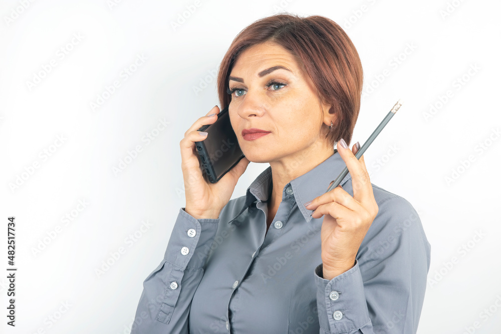 Business beautiful woman speaks on the phone with a pencil in her hand on a white background Business beautiful woman speaks on the phone with a pencil in her hand on a white background
