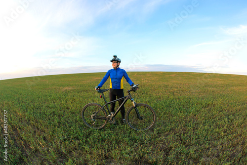 cyclist with Bicycle standing on field path