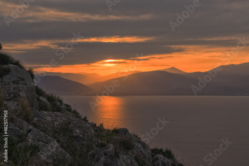 Sunset over the Argolic Gulf with cliff in foreground, Nafplion, Greece