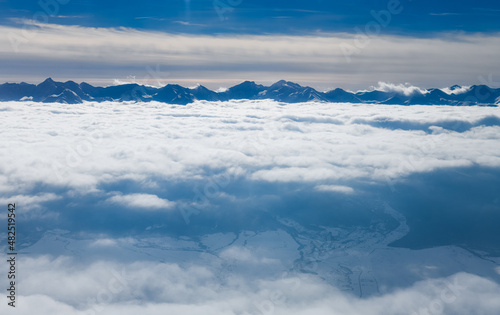Transylvania under the sea of clouds. Winter landscape at the bottom of Fagaras Mountains. Aerial view in a sunny day. © Dragoș Asaftei